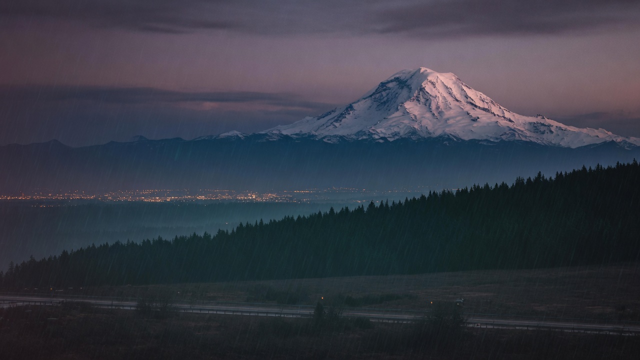 Mount Rainier at dusk above a rain-dark ridgeline
